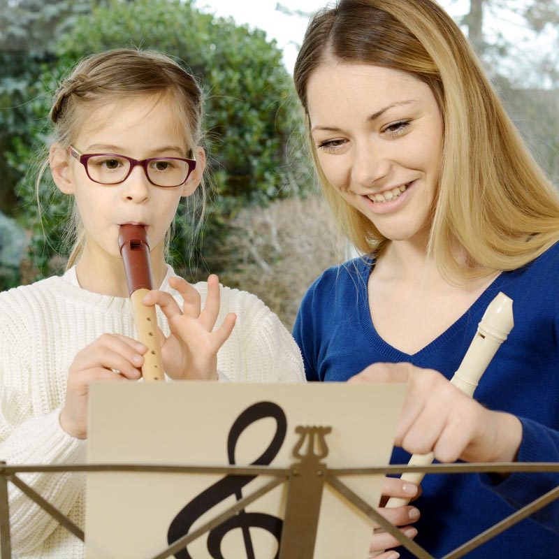 Kind mit Blockflöte beim Musikunterricht mit Musiklehrer